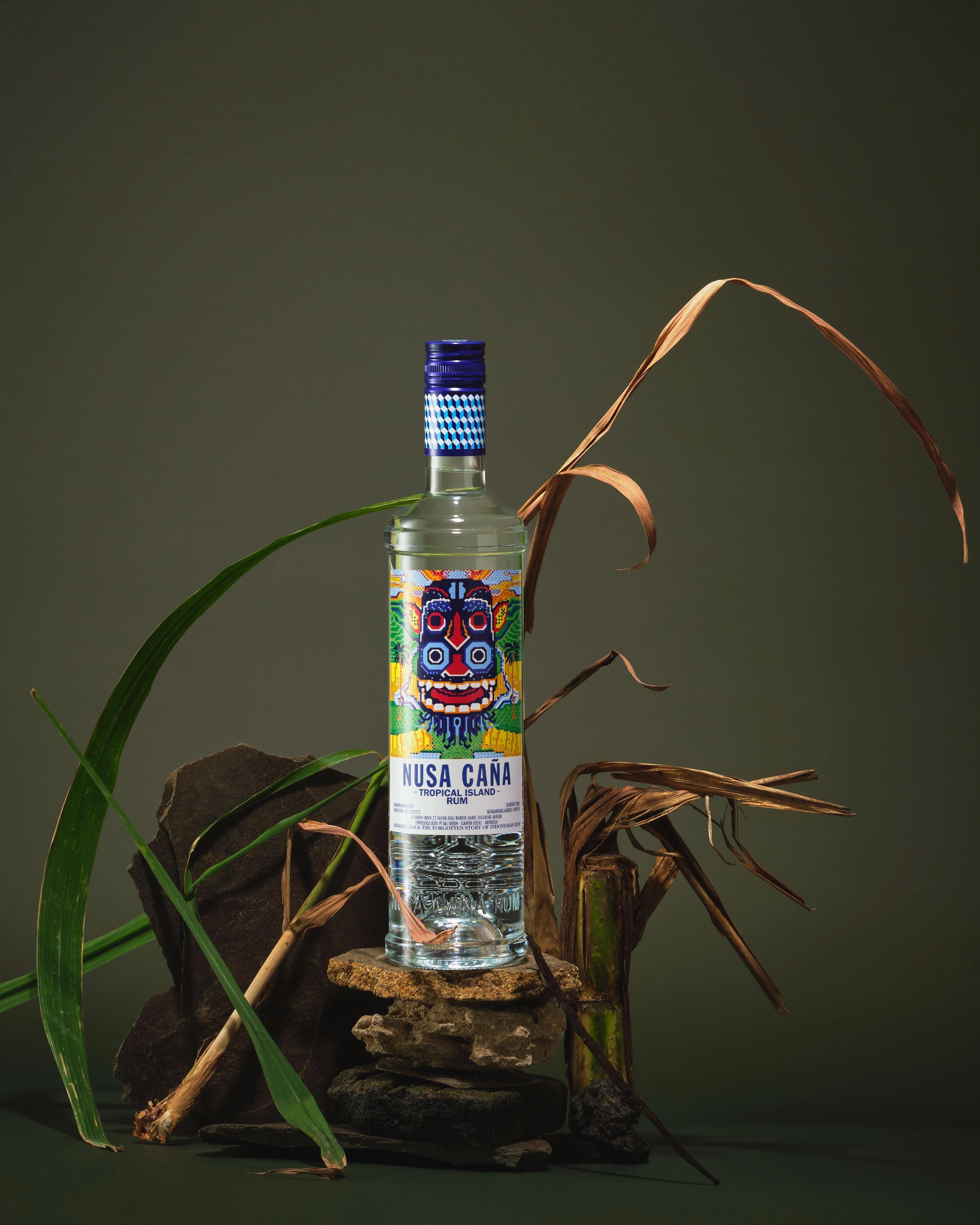 Nusa Caña Tropical Island rum bottle with a green background and foliage.